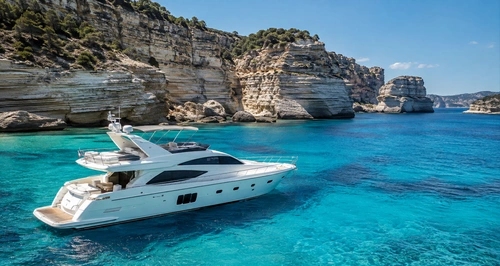 Yacht blanc devant les falaises et eaux turquoise de Corse