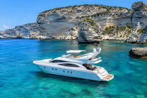Yacht au large d’une île grecque blanche et rocheuse